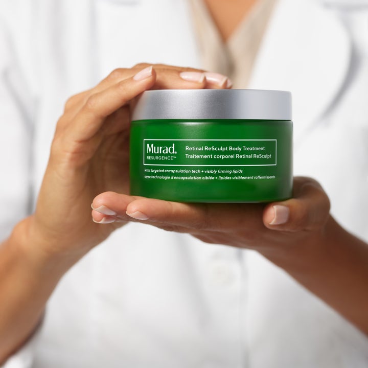 Murad Retinal ReSculpt Body Treatment 148 ml oppstrammende kroppskrem i grønn krukke med sølvlokk holdt i hendene.