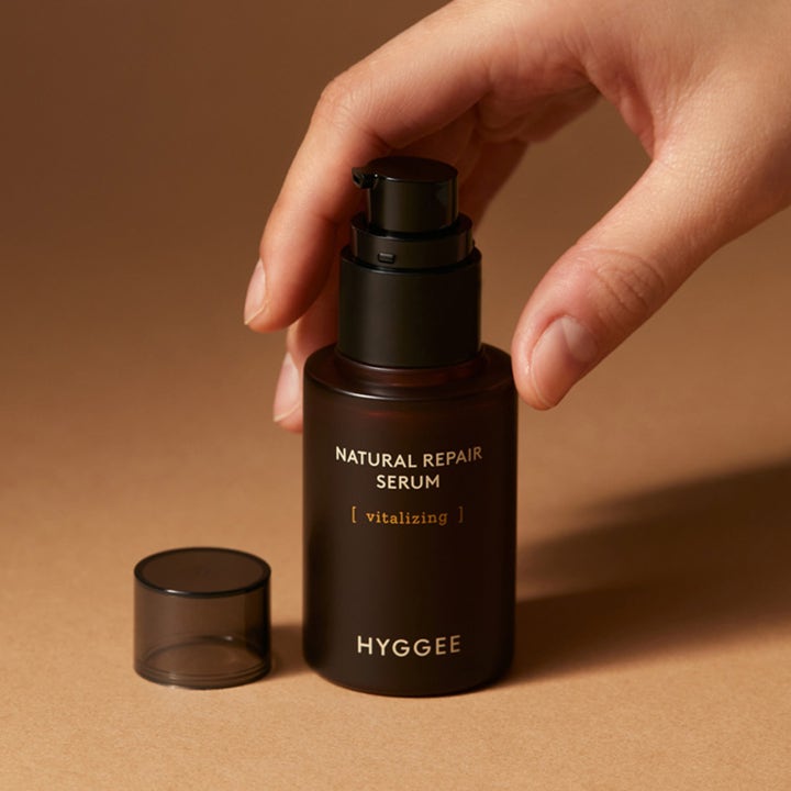 Hyggee Natural Repair Serum 30 ml vitaliserende ansiktsserum i mørkebrun flaske med svart pumpe og hånd