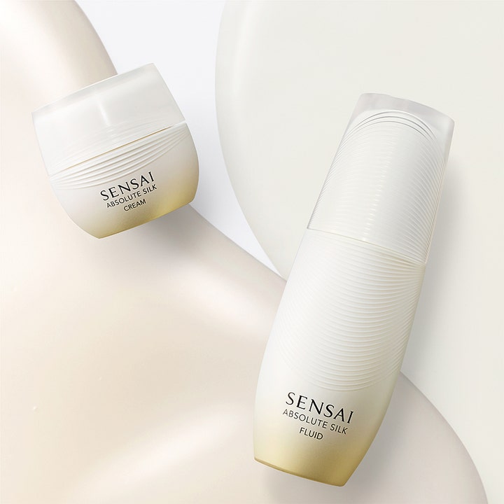 Sensai Absolute Silk Fluid 80 ml fuktighetsgivende ansiktskrem i hvit pumpeflaske og krukke med bølget tekstur
