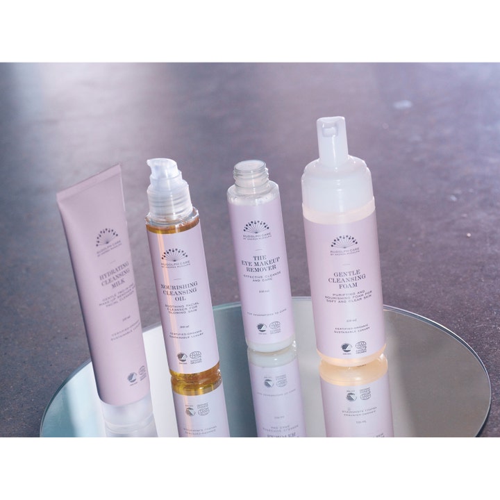 Rudolph Care The Eye Makeup Remover 100 ml skånsom sminkefjerner i lilla flaske stående på et rundt speil