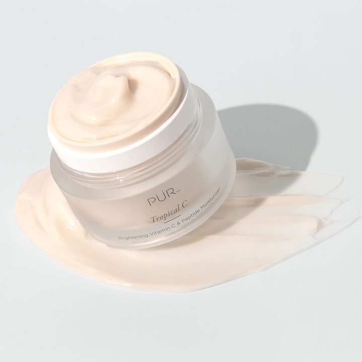 PÜR Tropical C Vitamin C & Peptide Moisturizer 50 ml opplysende dagkrem i frostet krukke på kremet ferskenfarget tekstur.
