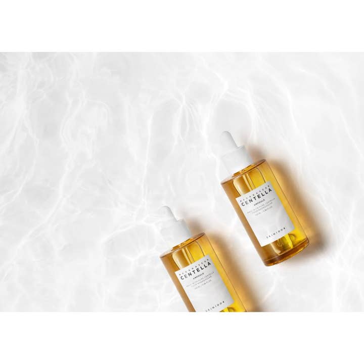 SKIN1004 Madagascar Centella Ampoule 100 ml beroligende serum i ravfargede flasker på en hvit vannoverflate