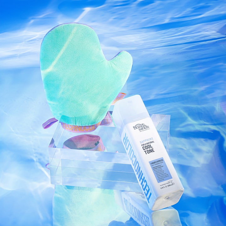 Bondi Sands Technocolor Sapphire 200 ml selvbruning gir kald tone med hvit flaske og grønn hanske over blått vann