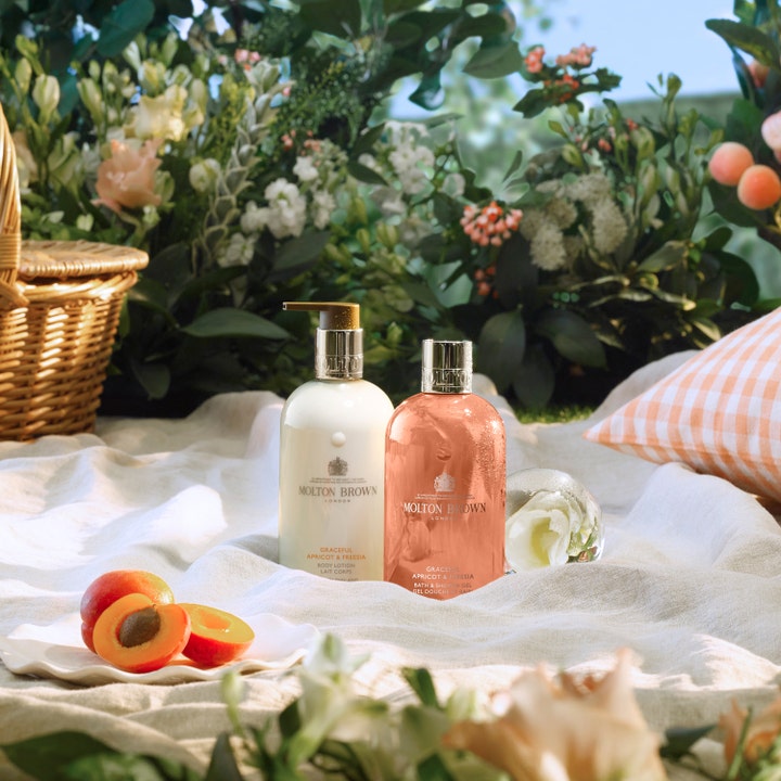 Molton Brown Graceful Apricot & Freesia Body Lotion 300 ml fuktighetsgivende kroppspleie i en piknik-setting med aprikoser
