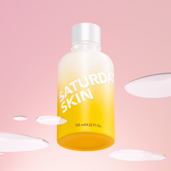 Saturday Skin Yuzu Vitamin C Brightening Toner 125 ml glødgivende toner i gul frostet flaske omgitt av klare dråper.