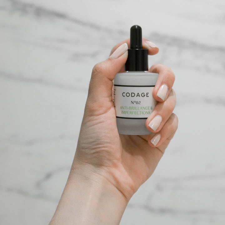 Codage Paris The Serum N°02 30 ml ansiktsserum mot urenheter i en frostet glassflaske med pipette i en hånd