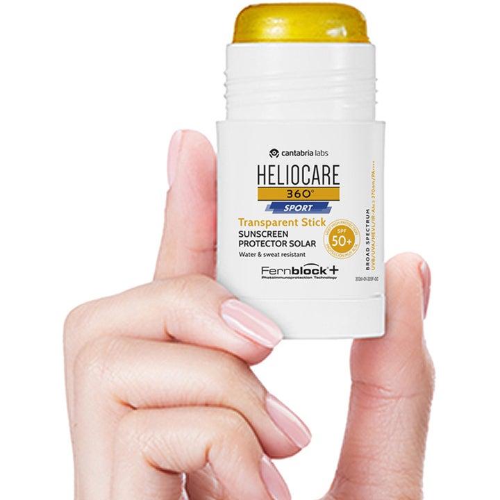 Heliocare Sport Stick SPF 50+ 25 g vannresistent solkrem i hvit stift med gjennomsiktig gul kjerne holdt i en hånd