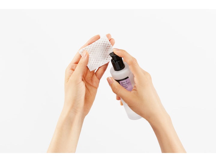 COSRX AHA 7 Whitehead Power Liquid 100 ml eksfolierende toner som pumpes på en hvit bomullspad fra en frostet flaske