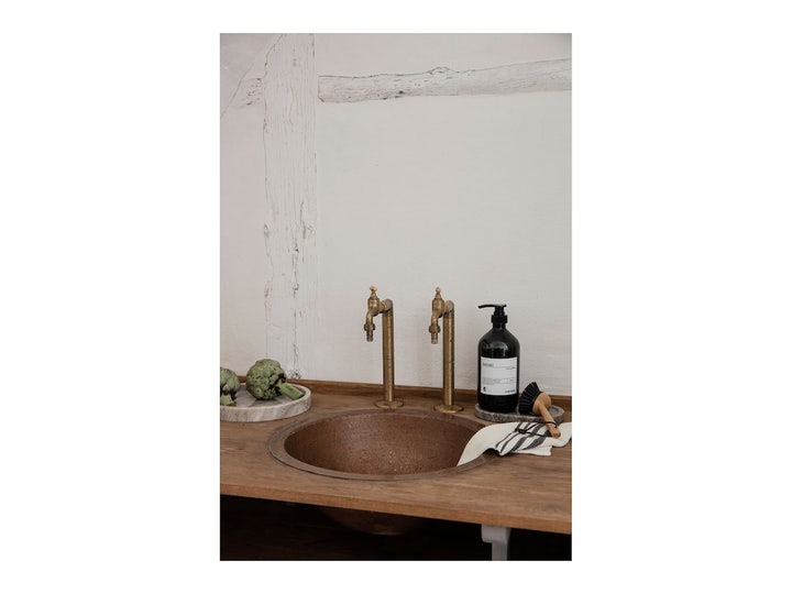 Meraki Forest Garden Clean Dishes 1000 ml oppvaskmiddel i mørk flaske ved en rustikk vask med messingkraner