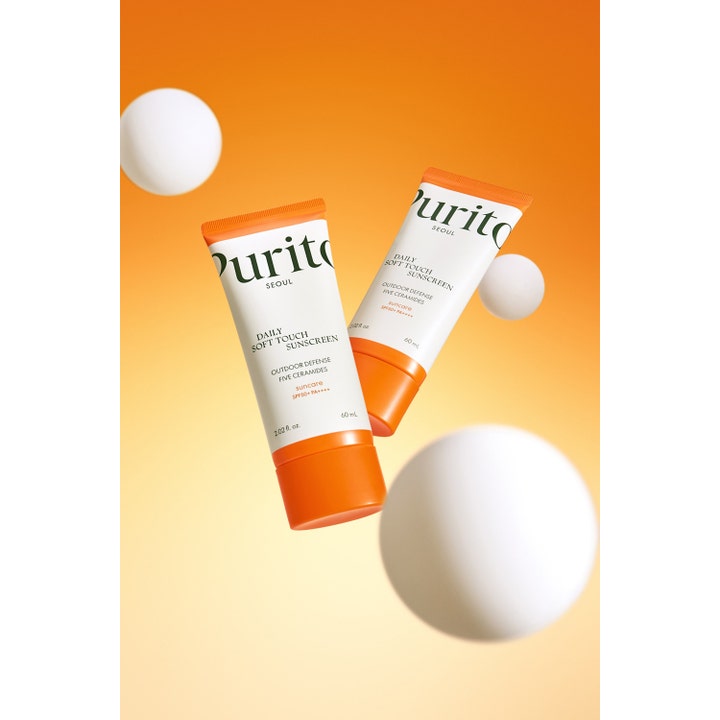 Purito Daily Soft Touch Sunscreen 60 ml beskyttende solkrem i to tuber med oransje korker og svevende hvite kuler