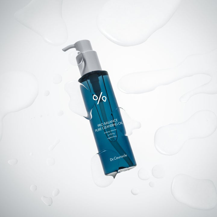Dr. Ceuracle Pro Balance Pure Cleansing Oil 155 ml rengjøringsolje i blå pumpeflaske omgitt av klare væskedråper