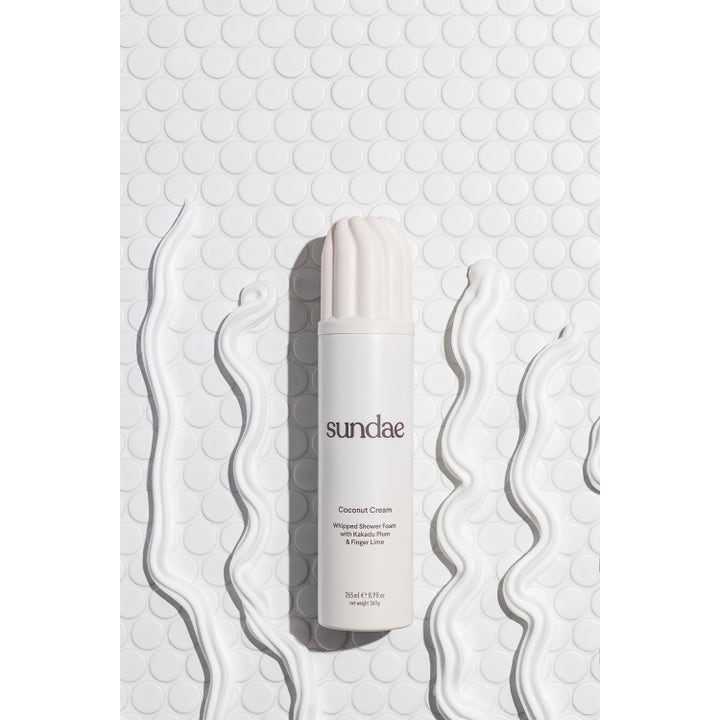 Sundae Whipped Shower Foam Coconut Cream 265 ml fuktighetsgivende dusjsåpe omgitt av bølger med kremet hvitt skum.