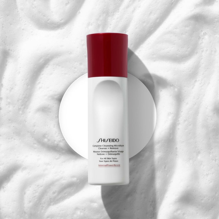 Shiseido Complete Cleansing Microfoam 180 ml rengjøringsskum i hvit flaske med rødt lokk omgitt av luftig skum