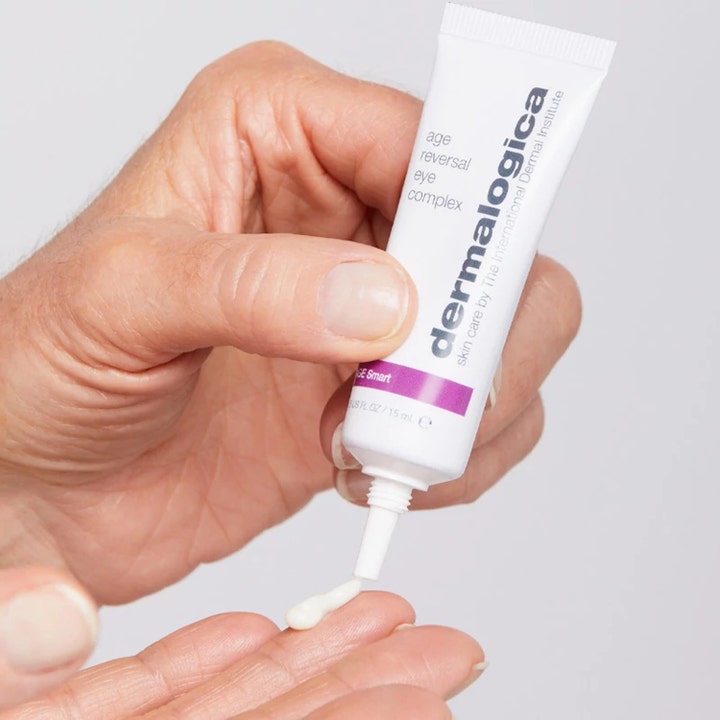 Dermalogica AGE smart Age Reversal Eye Complex 15 ml øyekrem i hvit tube som gir hvit krem på fingertuppene.