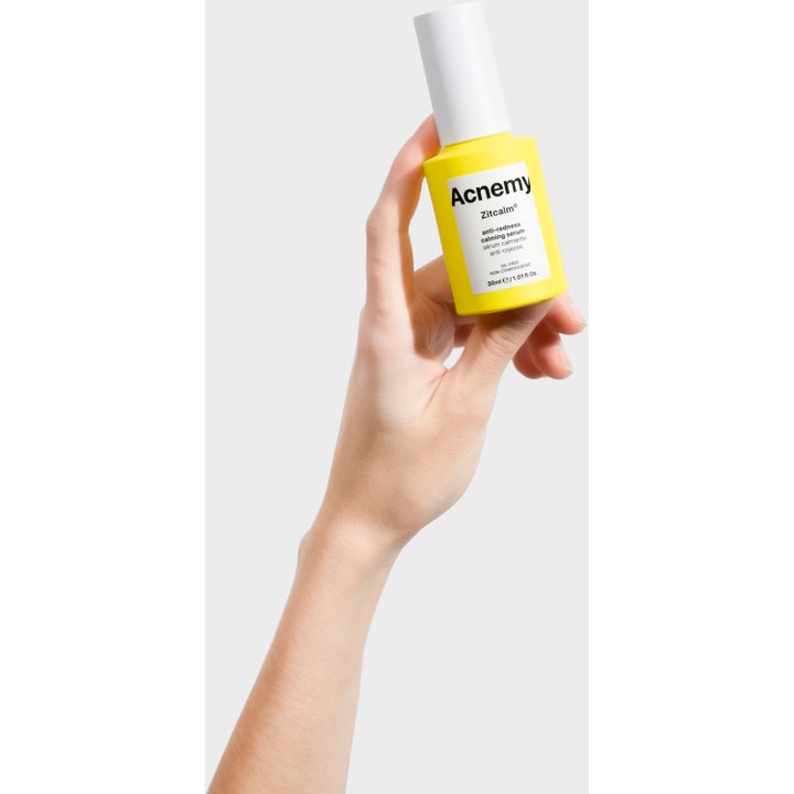 Niche Beauty Lab Acnemy Zitcalm Serum 30 ml beroligende ansiktsserum mot rødhet i gul flaske holdt av en hånd