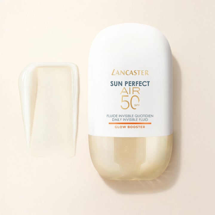 Lancaster Sun Perfect AIR Fluid 40 ml solkrem gir glød, hvit flaske med gullbase og en lyst skimrende teksturprøve.