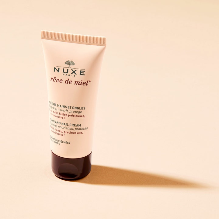 Nuxe Rêve de Miel Hand and Nail Cream 50 ml pleiende håndkrem i beige tube med mørkebrunt lokk på beige bakgrunn