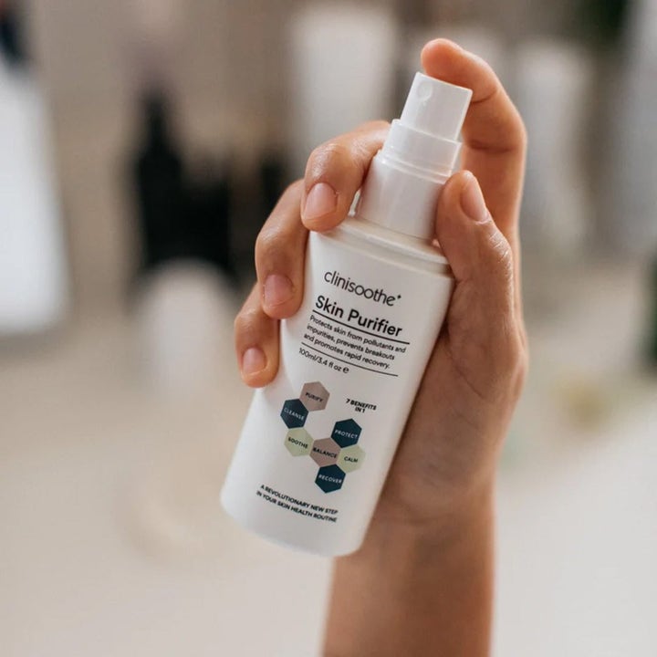 Clinisoothe Skin Purifier Spray 100 ml beroligende ansiktstoner i hvit sprayflaske holdt av en hånd.