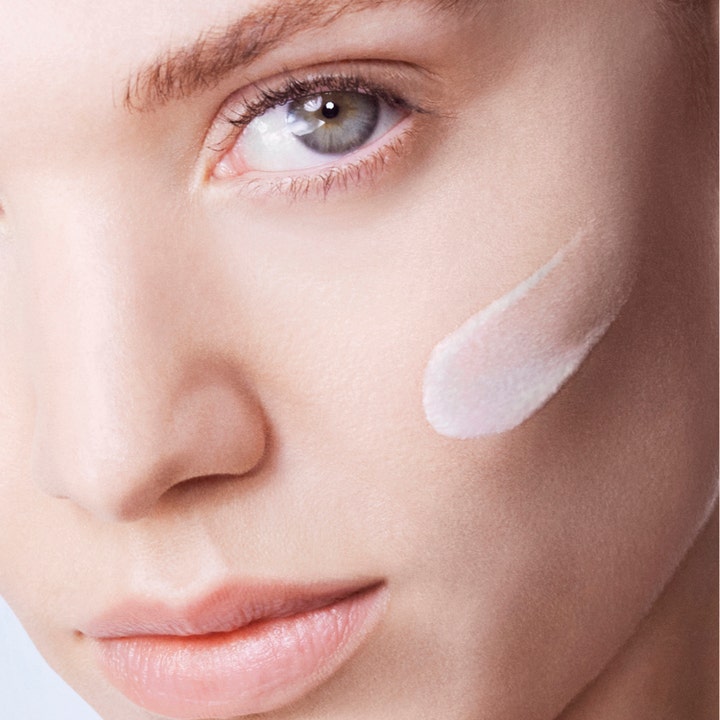 Lancôme UV Expert Supra Screen SPF50 40 ml solkrem som gir beskyttelse vist med hvit tekstur på et kinn