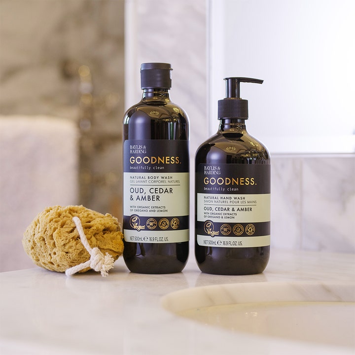 Baylis & Harding Goodness Body Wash 500 ml vegansk dusjsåpe i mørke flasker vist med en natursvamp på badet