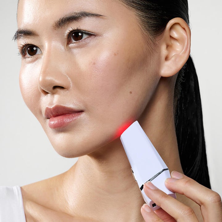 Currentbody Skin LED Blemish Pen hudpleieenhet som behandler kviser med rødt lys mot huden på kjevepartiet.