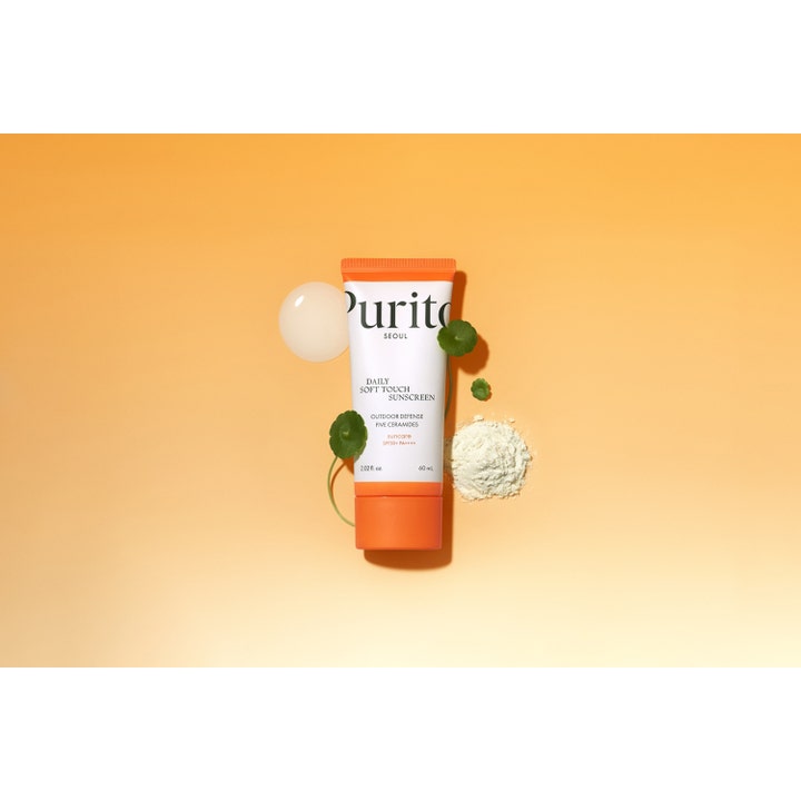 Purito Daily Soft Touch Sunscreen 60 ml ansiktssolkrem med SPF 50 og ceramider vist med grønne blader og hvit krem.