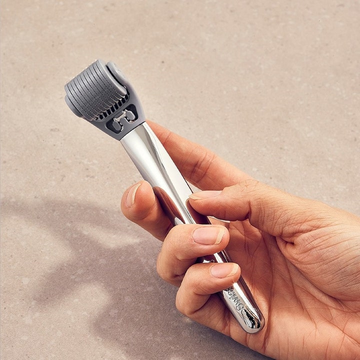 Swiss Clinic Skin Roller 0,5 mm 1 stk dermaroller stimulerer huden holdt i en hånd med sølvfarget håndtak.
