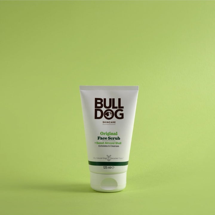 Bulldog Original Face Scrub 125 ml ansiktsskrubb med mandelskall som renser huden i hvit tube på grønn bakgrunn.