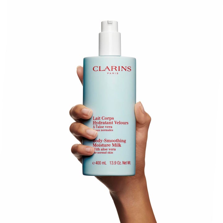 Clarins Hydrating Body-Smoothing Moisture Milk 400 ml fuktighetsgivende body lotion i lyseblå pumpeflaske holdt i en hånd