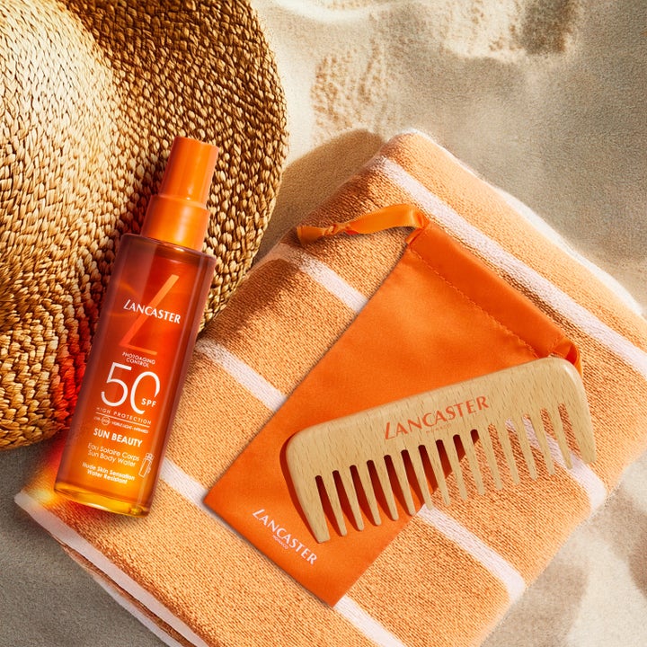 Lancaster Sun Beauty Body Sun Protective Water SPF50 100 ml solkrem på strandhåndkle med trekam og stråhatt