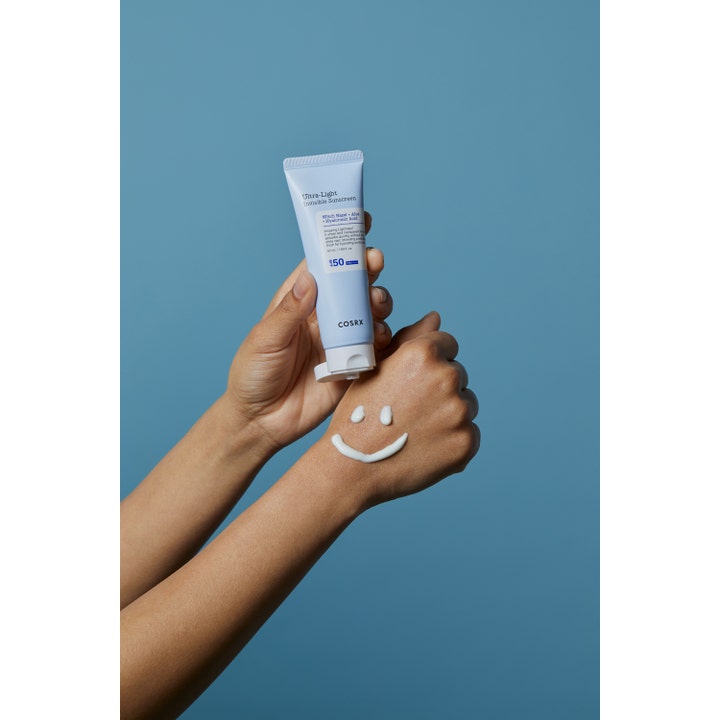 COSRX Ultra-Light Invisible Sunscreen SPF50 50 ml fuktighetsgivende solkrem i lyseblå tube med smilefjes på huden