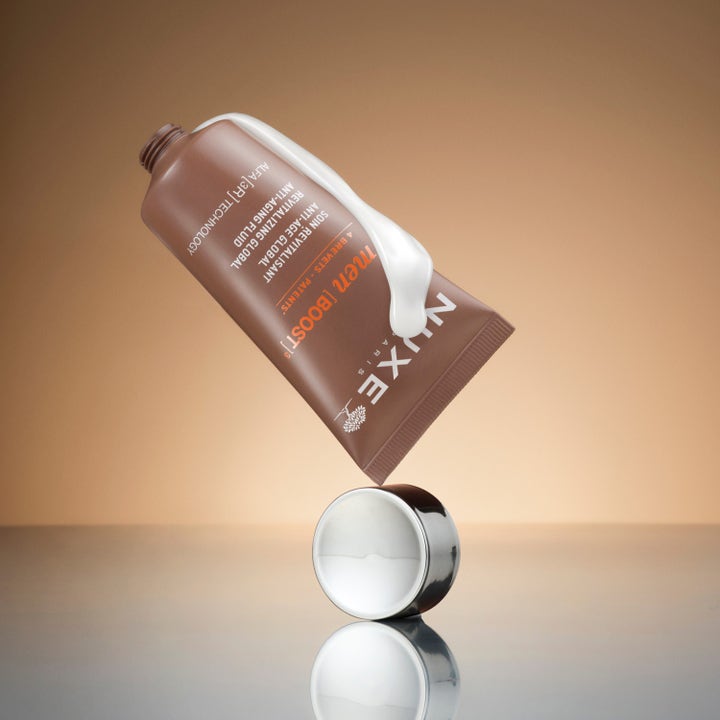 Nuxe Men Anti Age Cream 50 ml revitaliserende ansiktskrem i brun tube med hvit tekstur balansert på sølvlokk.