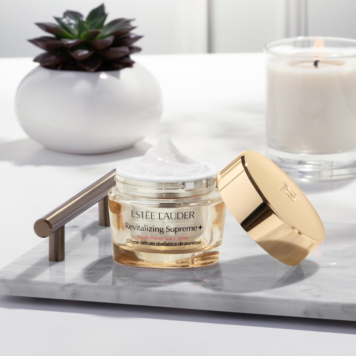 Estée Lauder Revitalizing Supreme + Soft Cream 30 ml dagkrem i åpen gullkrukke med hvit tekstur på et marmorbrett.