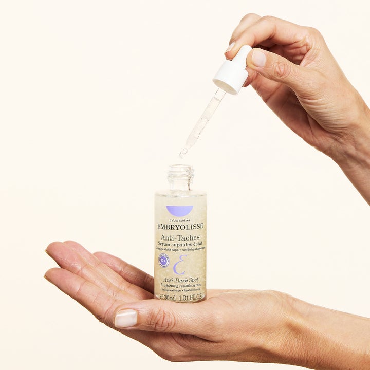 Embryolisse Concentrated Brightening Dark Spot Serum 30 ml i glassflaske holdes i en hånd med pipette