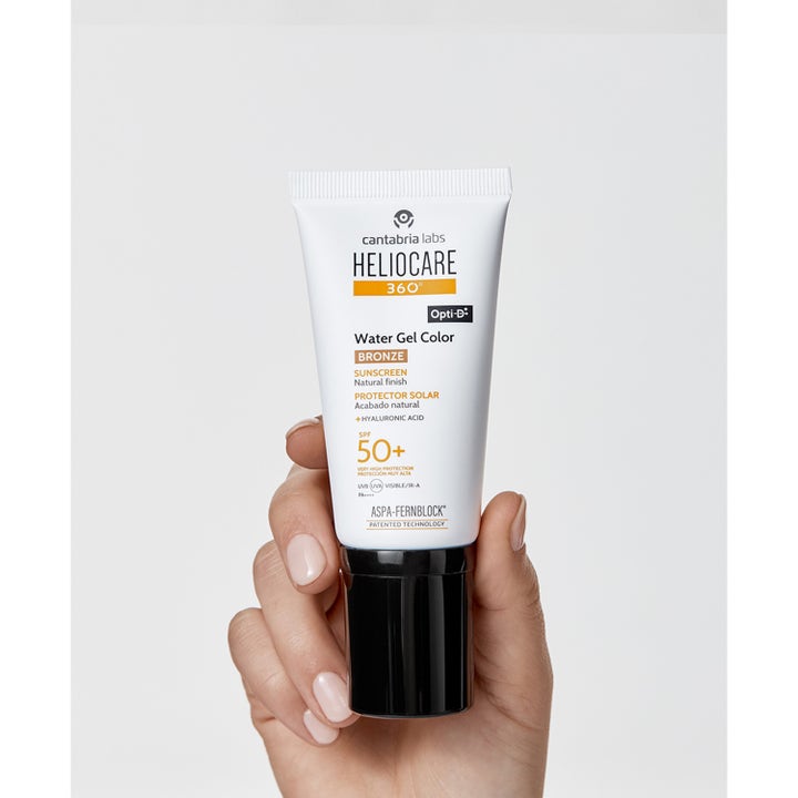 Heliocare Water Gel Color Bronze 50 ml fuktighetsgivende solkrem for ansiktet i hvit tube holdt i en hånd.