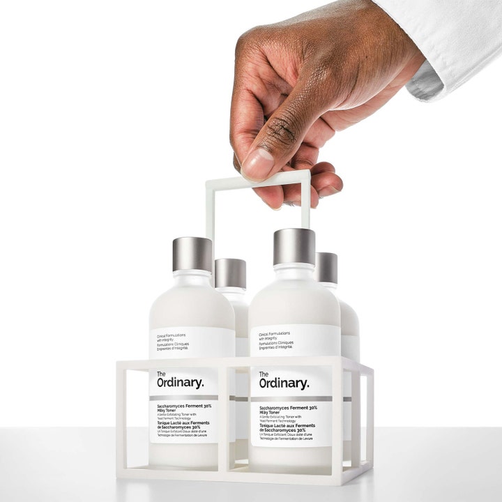 The Ordinary Saccharomyces Ferment 30% Milky Toner 100 ml eksfolierende toner i hvit holder holdt av en hånd