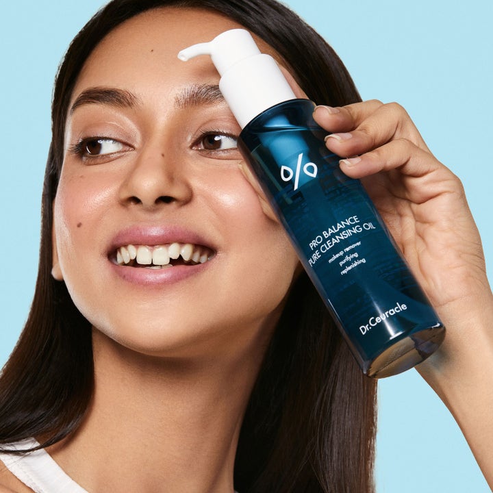 Dr. Ceuracle Pro Balance Pure Cleansing Oil 155 ml rensende ansiktsolje i blå flaske holdt av smilende kvinne