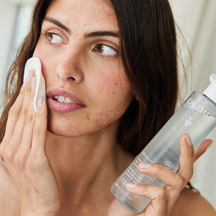 Caudalie Vinopure Purifying Toner 200 ml rensende ansiktsvann mot urenheter brukes av kvinne med bomullspad