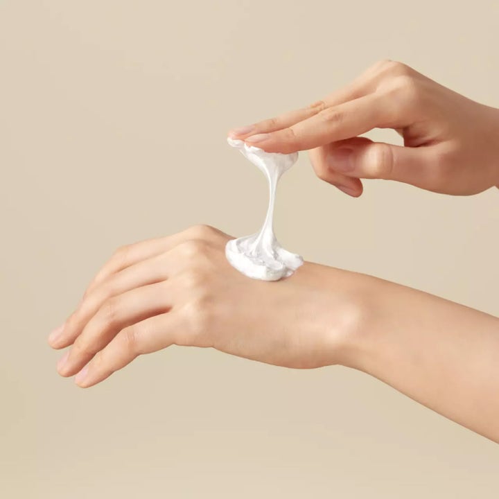 I'm from Rice Whip Facial Cleanser 150 ml ansiktsrengjøring med en hvit kremet og elastisk tekstur på en hånd.