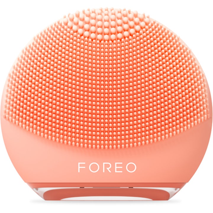 Foreo Luna 4 Go ansiktsrensebørste for glød i ferskenfarget silikon med tette massasje-nupper og hvit logo.