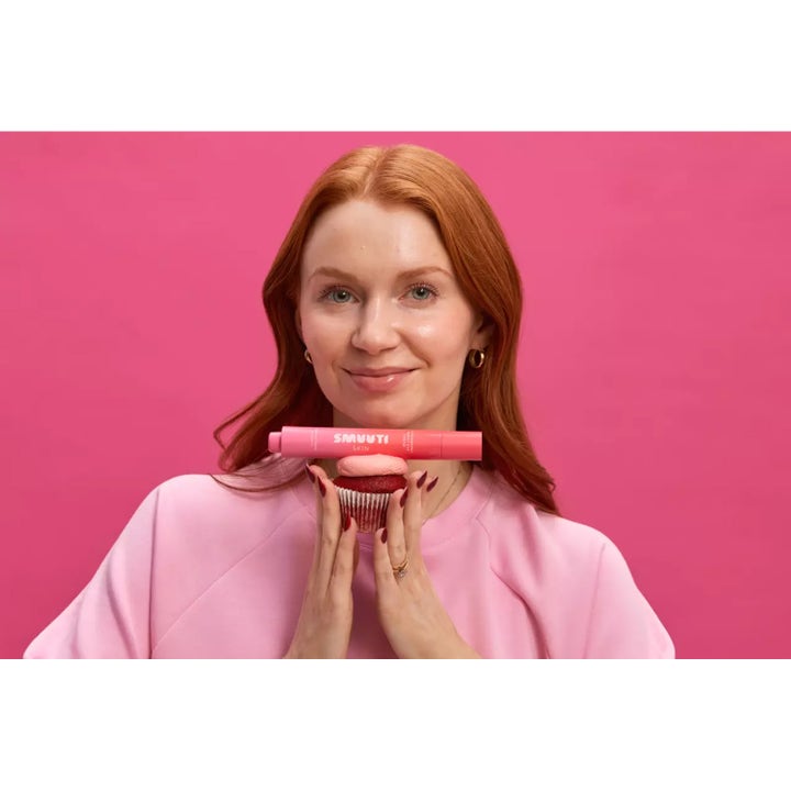 Smuuti Skin Strawberry Boost Eye Cream 15 ml pleiende øyekrem kvinne holder rosa tube balansert på en cupcake.