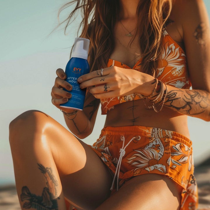 EVY Technology Daily Tan Activator & After Sun mousse beroliger huden holdt av kvinne i varmt sollys