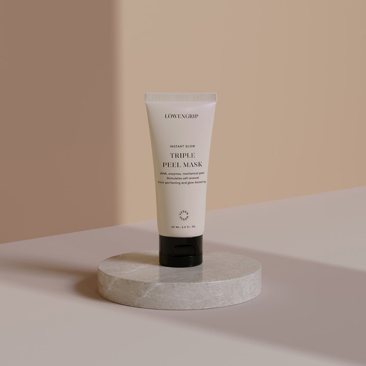 Löwengrip Instant Glow Triple Peel Mask 60 ml eksfolierende vegansk ansiktsmaske i beige tube på en rund marmorsokkel