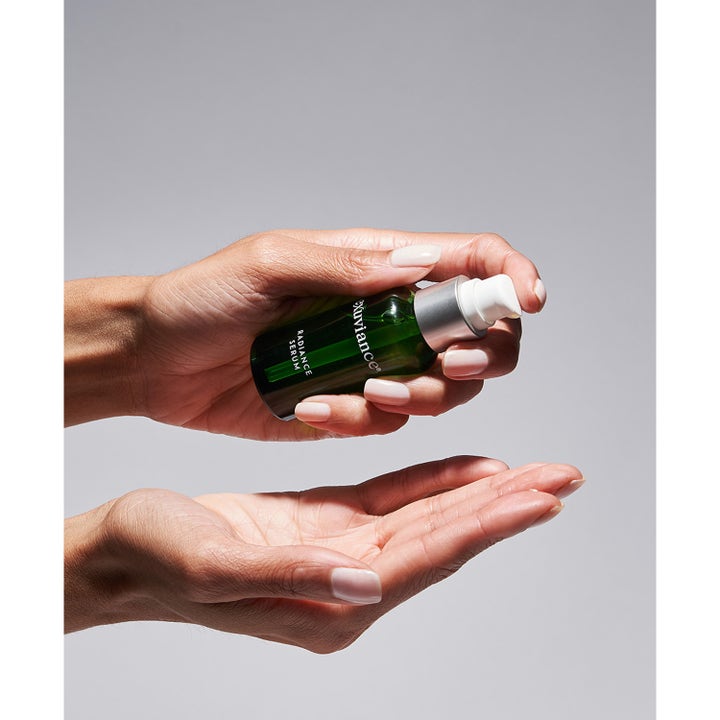 Exuviance Radiance Serum 30 ml glødgivende ansiktsserum i grønn glassflaske som pumpes ut i en håndflate