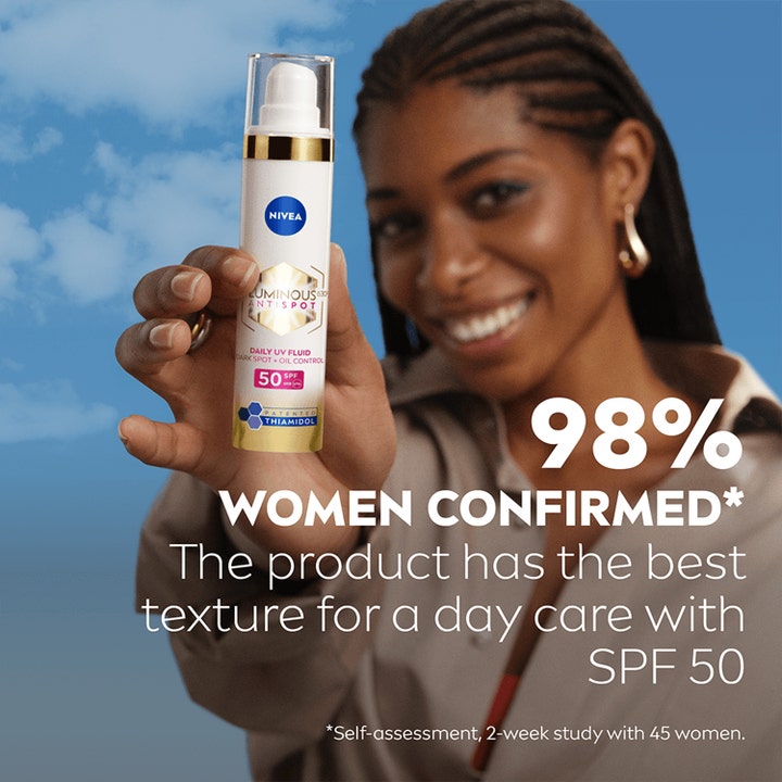 NIVEA Luminous630 Anti Dark-Spot Day Fluid 40 ml solkrem mot mørke flekker holdes av en kvinne mot blå himmel.