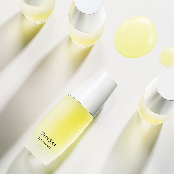 Sensai Dual Essence 30 ml fuktighetsgivende essence i frostet flaske med sølvkork og gule teksturdråper.