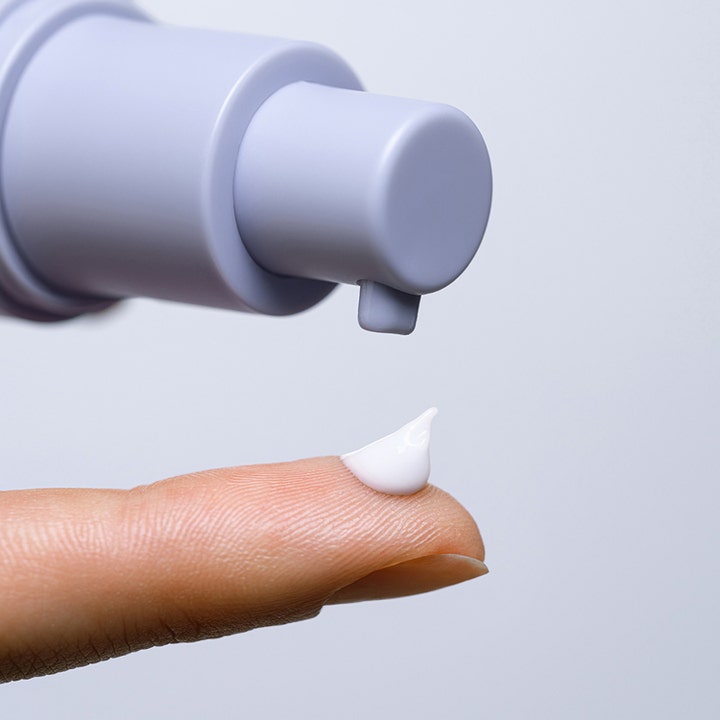 MÁDARA RETINOL ALTERNATIVE Eye Serum 15 ml øyeserum med hvit kremet tekstur på en finger og lilla pumpe.