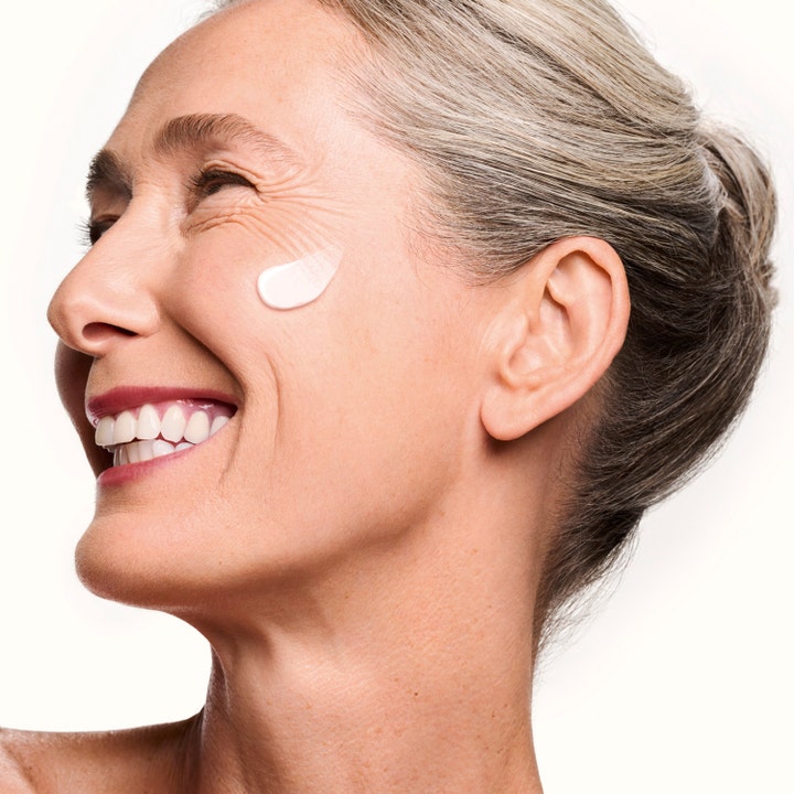 Shiseido Vital Perfection Concentrated Supreme Cream 50 ml løftende dagkrem på kinnet til en smilende moden kvinne