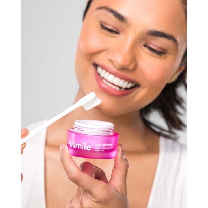 Hismile PAP+ Whitening Powder 12 g tannbleking gir et hvitere smil i rosa krukke holdt av smilende kvinne