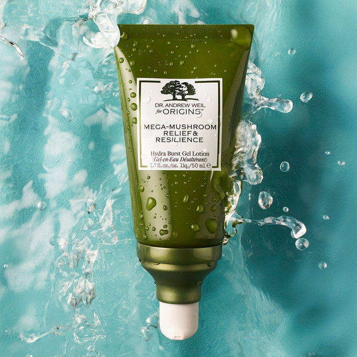 Origins Dr. Weil Mega-Mushroom 50 ml beroligende ansiktskrem i grønn tube omgitt av friskt sprutende vann
